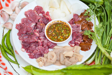 raw beef slice on plate with fresh vegetables and spicy sauce, beef sashimi meat - Thai food style...