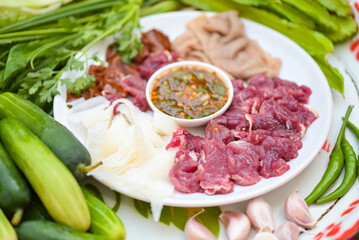 raw beef slice on plate with fresh vegetables and spicy sauce, beef sashimi meat - Thai food style spicy raw beef salad spicy minced meat salad