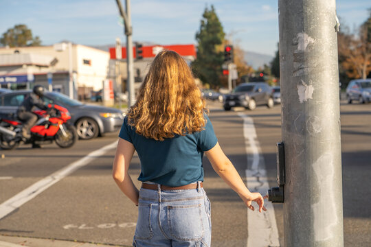 A young woman pressing the button to cross the road. 