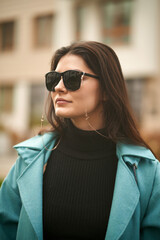 A confident and beautiful woman wears expensive sunglasses. Concept of luxury accesories for woman. Stylish brunette girl in the city