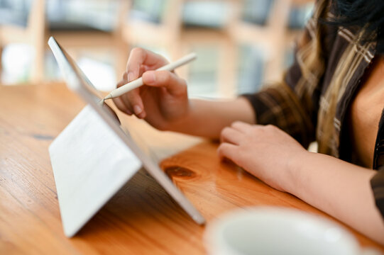Close-up, An Asian female using digital tablet to design her work while sitting in the cafe.
