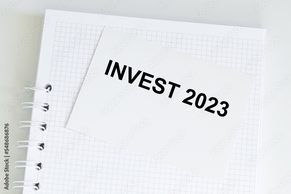 Poster invest 2023. text on a card against the background of a notebook on a bright table