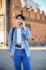 Obraz premium Handsome Asian male traveler talking on the phone while standing at Tha-Phae gate