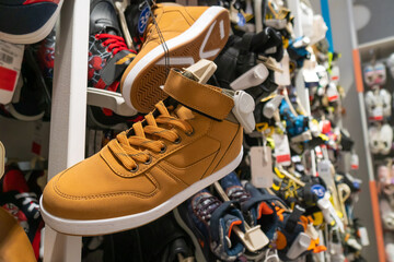 Close-up of casual men's sneakers in brown, red color in a shopping center store. Many shoes...