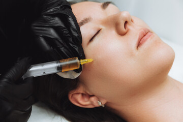 A cosmetologist performs plasmolifting on the face of a beautiful woman in a beauty salon. The...
