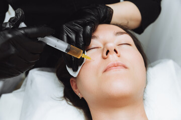 A cosmetologist performs plasmolifting on the face of a beautiful woman in a beauty salon. The concept of cosmetology.