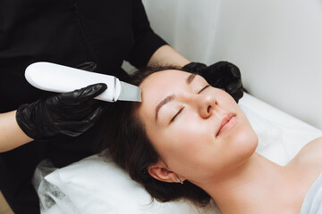 Obraz na płótnie Canvas Skin care. Close-up Of A Beautiful Woman Receiving An Ultrasound Facial Peeling. Ultrasonic skin cleaning procedure. Cosmetic procedures. Cosmetology.