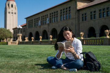 concentrate asian korean female international student reviewing notes for test on the lawn near hoover tower during her spring semester study tour at school university in California usa