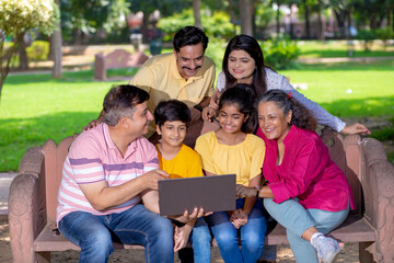 Fototapeta na wymiar Happy indian or asian family using laptop at park