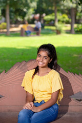 Indian little girl sitting on bench at park