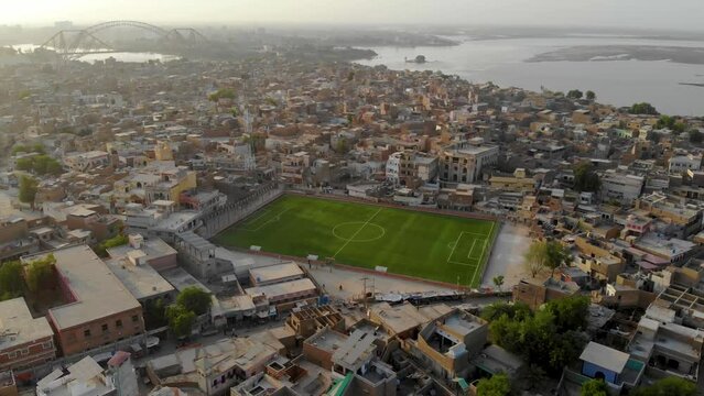 Aerial view of a football pitch, fields and homes on public recreation ground. Aerial shot of Rohri city with football ground in the middle of the city.