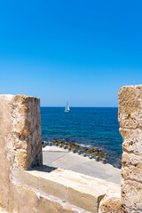 View through the battlements of the Firka Venetian Fortress on a sailing ship sailing on the sea of ​​Crete near Chania, Crete