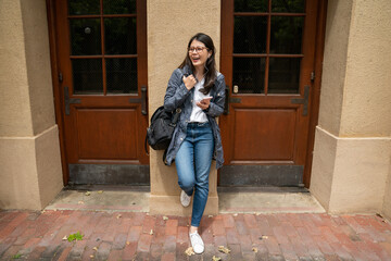 full length of smiling asian korean college girl relaxing against pillar between two wooden doors...