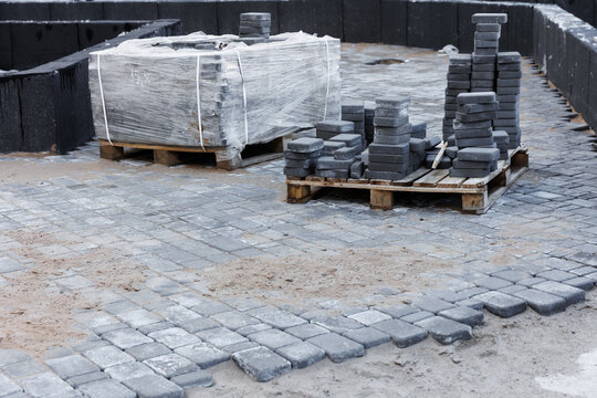 Paving Tiles For Paving Sidewalks. 
Pallets And Packages Of Fresh Concrete Tiles In The Construction Warehouse Outside. The Concept Of Repair And Building Materials. Top View. 