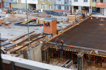 Construction workers are busy with their work. Construction of a residential house in the summertime. The concept of a construction site. 