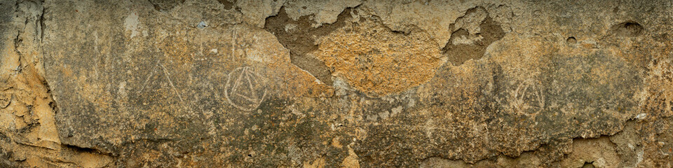 widescreen dark beige background of an old abandoned weathered exterior wall with peeling off cement stucco for art design or creative backdrop