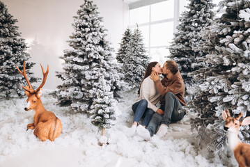 Fototapeta na wymiar A couple stay on the snow in the Christmas forest