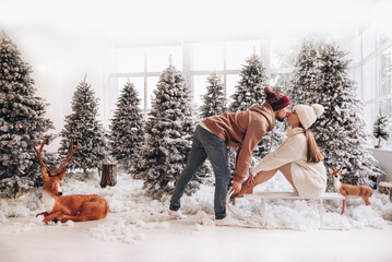 A couple stay on the snow in the Christmas forest