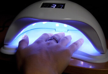 Home manicure with a lamp for drying nails. Close-up