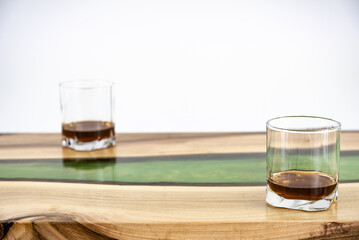 Coffee table, living room table. Resin handmade wood table. On a white background. Glass of whisky and glass of wine on the table.