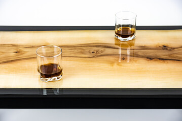 Coffee table, living room table. Resin handmade wood table. On a white background. Glass of whisky and glass of wine on the table.