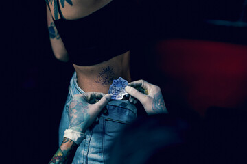 Close-up hands of master Tattoo artist in white gloves sticking paper with pattern on client hand...