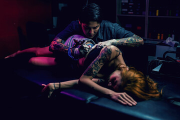 Professional tattooist makes the tattoo on a girl waist, focusing on tattoo machines in a modern...