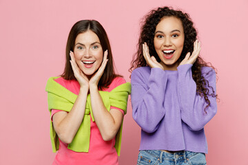Young two friends surprised shocked impressed exultant women wears green purple shirts together...