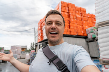 Portrait of positive caucasian male supervisor standing in warehouse of hardware store. Happy millennial man in store building materials