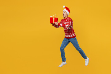 Full body side view fun merry young man wear red Christmas sweater Santa hat posing jump high run...