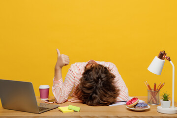 Young sleepy employee business woman wear casual shirt sit work at office with pc laptop put head down on desk sleep show thumb up isolated on plain yellow color background Achievement career concept.