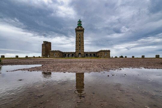 Cap Frehel lighthouse on a rainy day with a dramatic sky in the background, France
