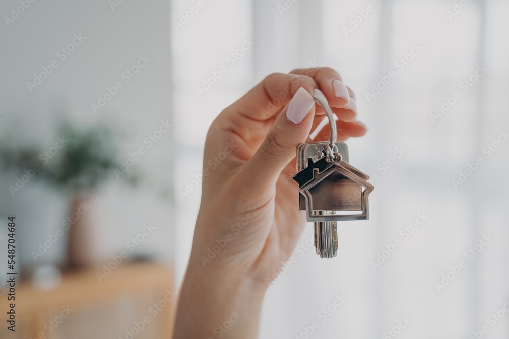 Wall mural Key to new home. Close up female hand holding house keys. Real estate agent offers apartment