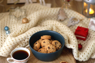 Various Christmas decorations, cup of tea or coffee, sweets, small presents, knitted blanket and candles. Selective focus.