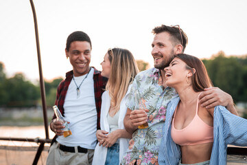 Group of multietnical friends enjoying on river boat party, drinking beer having a great time
