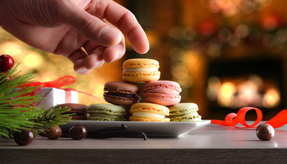 Hand picking up a chocolate macaron from a plate