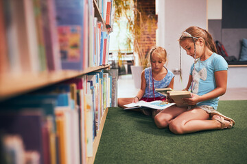 Schoolgirls looking for book for reading in school library. Students choosing books for reading....