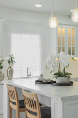 Beautiful orchid flowers on white marble table in kitchen. Luxury interior
