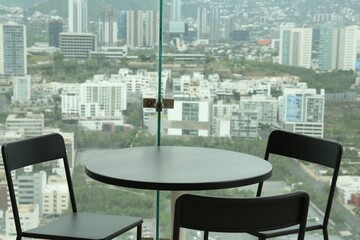 Obraz premium Coffee table and chairs against picturesque landscape of city in cafe