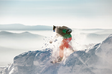 Man snowboarder jumps from snowdrift with powder snow - obrazy, fototapety, plakaty