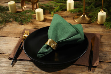 Stylish table setting with green fabric napkin, beautiful decorative ring and festive decor on wooden background