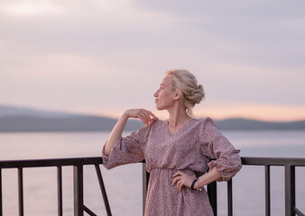girl on the pier against the background of a blurry, pink sunset
