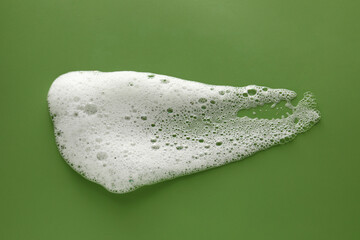 Smudge of white washing foam on olive background, top view