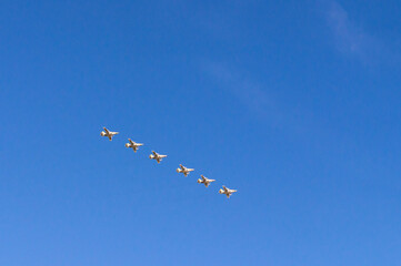 Fototapeta na wymiar Aerobatic group of planes and blue sky. Performance in the sky and demonstration of aerobatics. Spatial maneuvering of the aircraft. The flight of the plane.