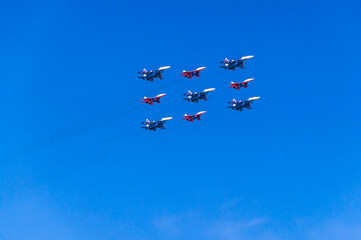 Aerobatic group of planes and blue sky. Performance in the sky and demonstration of aerobatics. Spatial maneuvering of the aircraft. The flight of the plane.