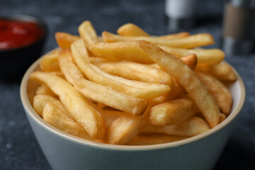Delicious fresh french fries in bowl on black table, closeup