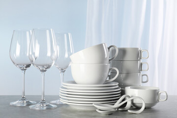 Fototapeta na wymiar Set of clean dishware and glasses on grey marble table