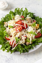 Traditional caesar salad with chicken on a plate on white table with napkin fork and knife.