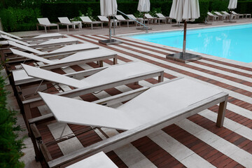 Many sunbeds and umbrellas near outdoor swimming pool