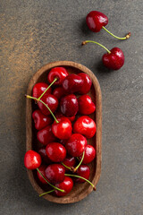Ripe sweet cherries on oval wooden plate shot from above